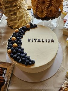 Močiutės jubiliejaus tortas su užrašu „Vitalija“, šilauogėmis ir auksiniais papuošimais